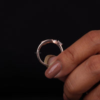 Rose gold ring with diamonds held by a hand on a black background, Pear Shape Moissanite Bypass Ring – Baguette Channel Set Open End Fashion Ring