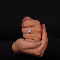 Two hands holding a diamond ring against a black background, Rose Gold Bypass Ring – Pear & Baguette Moissanite Channel Set Open Gap Design