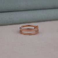 Rose gold ring with small diamonds on a neutral background