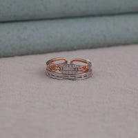 Two rose gold and silver rings stacked on a neutral background