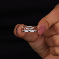 Hand holding two diamond rings against a black background