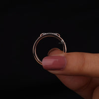 Rose gold ring with diamonds held by a hand against a black background
