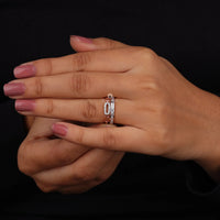 Close-up of a hand wearing a silver ring with a central gemstone on a black background