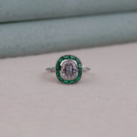 Elegant ring with emerald and diamond design on a neutral background
