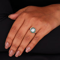 Hand wearing a ring with a green gemstone on a black background