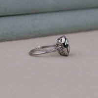 Silver ring with a heart-shaped gemstone on a neutral background