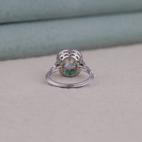 Silver ring with a green gemstone on a light gray surface