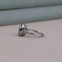 Silver ring with a green gemstone on a neutral background