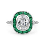 Diamond ring with emerald green gemstones on a white background