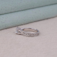Silver ring with intricate design on a light surface, Vintage Style Round Moissanite Solitaire Engagement Ring with Filigree and Milgrain Design