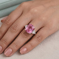 Pink gemstone ring on a person's finger with a soft background