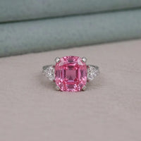 Ring with a pink gemstone and diamond accents on a neutral background
