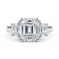 Diamond ring with emerald-cut stones on a white background