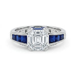 Elegant ring with emerald-cut diamond and blue gemstones on a white background