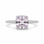 Ring with a pink gemstone and diamond-studded band on a white background