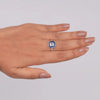 Ring with a blue gemstone on a hand against a gray background, sapphire accented asscher wedding ring, 1920s inspired sapphire ring, vintage inspired sapphire bridal jewelry