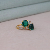 Gold ring with two green gemstones on a light gray surface, Elegant Two Stone Engagement Band, CZ Bypass Ring For Bride, Classic Asscher Cut CZ Engagement Jewelry.
