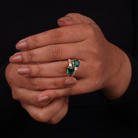 Hand wearing a ring with emerald stones on a black background, Affordable CZ Wedding Jewelry, Elegant Green CZ Promise Ring, Modern Bypass Engagement Ring