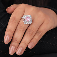 Close-up of a hand wearing a ring with a pink gemstone on a dark background, Pink Cushion & Multi Cut CZ Stone Halo Cocktail Party Wear Ring