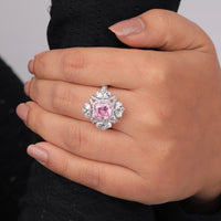 Hand wearing a ring with a pink gemstone and diamond-like stones on a neutral background, pink cushion halo cocktail ring, multi cut cz stone party wear ring, cushion cut pink stone halo ring,