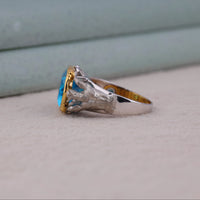 Silver ring with a blue gemstone and gold accents on a light gray surface, Fashion Forward Aqua Man Character Jewelry, Hero Inspired Statement Jewelry Accessory, Collectible Poseidon Superhero Inspired Ring