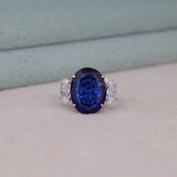 Ring with a blue gemstone and clear stones on a neutral background, Blue Sapphire Accent Oval CZ Three Stone Engagement & Wedding Ring
