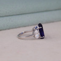 Silver ring with a blue gemstone and diamond on a light gray surface, Oval White CZ with Blue Sapphire Three Stone Engagement Wedding Band