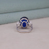 Silver ring with a blue gemstone on a neutral background, Oval Blue Sapphire & CZ Three Stone Bridal Engagement Ring