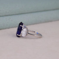 Silver ring with a blue gemstone and diamond on a light gray surface, blue sapphire engagement ring, oval CZ three stone ring, sapphire and white stone wedding ring, sapphire cubic zirconia bridal ring