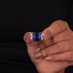 Hand holding a ring with a blue gemstone against a black background, 