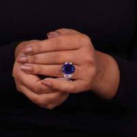Hand wearing a ring with a blue gemstone on a black background, Three Stone Oval White CZ and Blue Sapphire Engagement Ring for Women