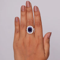 Ring with a purple gemstone on a hand against a plain background, Blue Sapphire Cushion Halo Ring with Round CZ, Anniversary Gift
