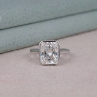 Silver ring with a large rectangular diamond on a light pink surface.