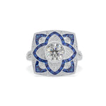Elegant ring with blue gemstones and diamond-like center on a white background
