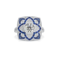 Elegant ring with blue gemstones and diamond-like center on a white background