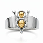 Silver ring with gold skull designs and a diamond on a white background