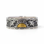 Silver ring with black and white pattern and gold accent on a white background