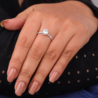 Close-up of a hand wearing a diamond ring with a dark background, Round Moissanite Hidden Halo Engagement Ring, Moissanite Engagement Ring, Hidden Halo Moissanite Ring