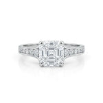 Diamond ring with a central emerald-cut diamond and smaller diamonds on the band against a white background