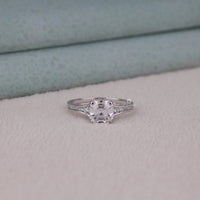 Silver ring with a large central gemstone and smaller stones on a soft fabric background