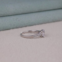 Silver ring with a diamond on a light gray surface