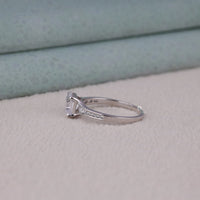 Silver ring with a diamond on a light gray surface
