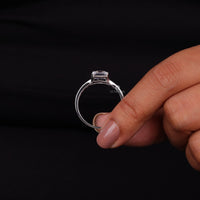 Hand holding a clear ring with 'OCTA' branding against a black background