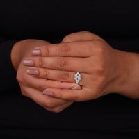 Close-up of a hand wearing an engagement ring with a black background