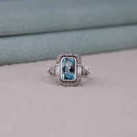 Silver ring with a blue gemstone on a light gray background