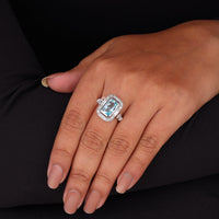 Close-up of a hand wearing a ring with a large gemstone on a black background