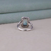 Silver ring with a blue gemstone on a light gray surface