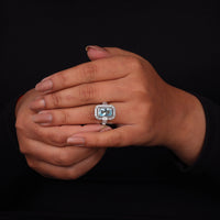 Hand wearing a ring with a blue gemstone on a black background