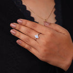 Hand wearing a ring with a blue gemstone against a dark background, Emerald Cut Rainbow Moonstone Ring