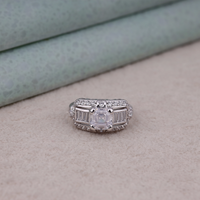 Silver ring with a large central diamond and smaller diamonds on a soft surface